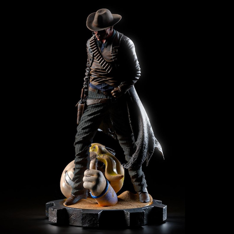 May include: A detailed figurine of a cowboy in a brown hat and duster coat, with a gun in a holster. The figure stands on a base with a thumbs-up hand and a money bag. The figure is in a dramatic pose, with a dark background.