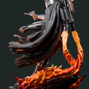 May include: A detailed statue of The Mandalorian, a character from the Star Wars franchise, with a blaster in hand. The figure is clad in silver armor and a dark cape, with a jetpack and Grogu on his back. The base features fiery orange and yellow flames.