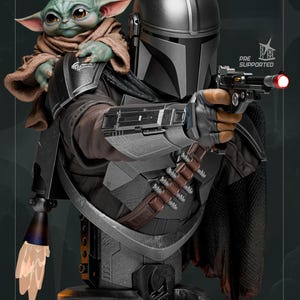 May include: A detailed bust of The Mandalorian holding a blaster, with Grogu perched on his shoulder. The figure is predominantly gray and black, with brown accents. The text "PRE SUPPORTED" is visible. A light effect emanates from the blaster.