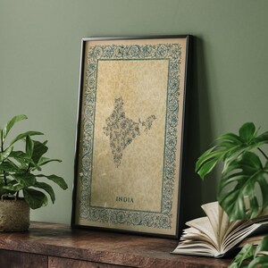 May include: A framed vertical print featuring a map of India filled with intricate blue floral patterns on a beige background. The map is surrounded by a decorative blue floral border and the word INDIA is printed in blue at the bottom centre.