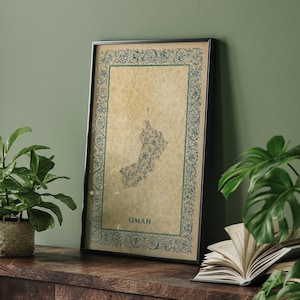 May include: A framed vertical wall art print featuring a map of Oman in a floral pattern. The map is centered on a beige parchment-style background, surrounded by a decorative blue border of intricate vines and leaves, with the word OMAN below.