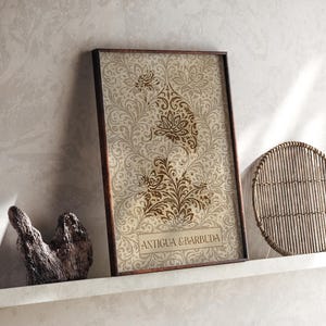 May include: A rectangular framed print featuring a beige and brown damask pattern with a central floral motif and the text ANTIGUA & BARBUDA printed in a rectangular box at the bottom. The artwork is displayed in a dark brown wooden frame.
