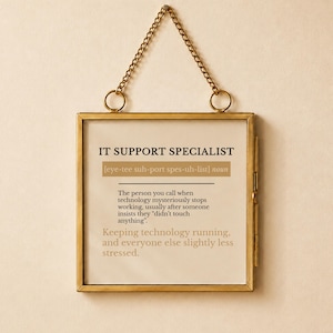 Puede incluir: Un marco de metal cuadrado de tono latón con una cadena para colgar que contiene una definición impresa de un especialista en soporte técnico. El texto dice: IT SUPPORT SPECIALIST [eye-tee suh-port spes-uh-list] noun. The person you call when technology mysteriously stops working, usually after someone insists they didn't touch anything. Keeping technology running, and everyone else slightly less stressed.