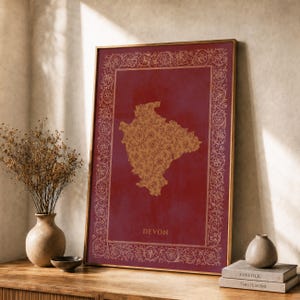 Puede incluir: Una impresión rectangular enmarcada con un fondo rojo intenso y un mapa central de Devon relleno con un patrón floral dorado. La impresión está rodeada por un intrincado borde floral dorado e incluye la palabra DEVON impresa en oro en la parte inferior.