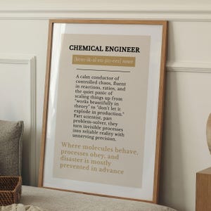 Op de afbeelding: Een ingelijste print met een licht houten frame. De print bevat bovenaan de woorden "CHEMICAL ENGINEER" in vette zwarte tekst, gevolgd door een definitie. De definitie beschrijft de rol van een chemisch ingenieur. De achtergrond is lichtbeige.