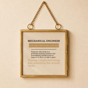 Op de afbeelding: Een vierkante wandhanger met een messing frame en een gedrukte definitie van een werktuigbouwkundig ingenieur. De tekst luidt: MECHANICAL ENGINEER [muh-kan-i-kul en-juh-neer] noun. Someone who looks at a perfectly working machine and immediately wonders how to improve it, fix it, or take it apart. Turning complicated things into something that actually works.