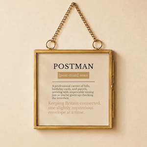 Könnte beinhalten: Ein quadratischer Wandbehang mit Messingrahmen, der eine wörterbuchartige Definition des Wortes POSTMAN zeigt. Der Text beschreibt einen professionellen Zusteller von Rechnungen, Geburtstagskarten und Paketen, ergänzt durch einen Satz über Großbritannien.
