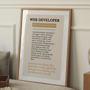 Peut inclure: Une affiche encadrée avec le texte "WEB DEVELOPER" en gras. L'affiche comprend une définition d'un développeur web, décrivant son travail avec le code, les frameworks et les bugs. Le cadre est de couleur marron clair.