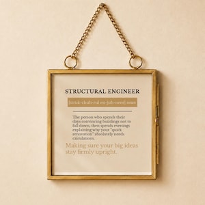May include: A square wall hanging in a brass metal frame with a gold chain. The print features the text STRUCTURAL ENGINEER, a phonetic pronunciation, and a humorous definition about convincing buildings not to fall down and needing calculations.