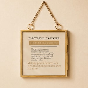 May include: A square brass-framed wall hanging featuring a definition of an electrical engineer. The text reads: ELECTRICAL ENGINEER [i-lek-tri-kal en-juh-neer] noun. The person who makes electricity behave, fixes mysterious faults, and quietly judges your wiring. Basically, turning sparks, circuits, and chaos into something that actually works. Making power behave, one circuit and questionable wire at a time.