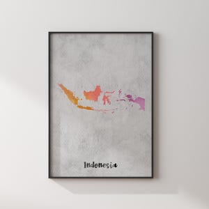 May include: A framed wall art print featuring a watercolour map of Indonesia in gradient shades of orange, red, and purple against a textured light grey background. The word Indonesia is printed in black script at the bottom of the print.