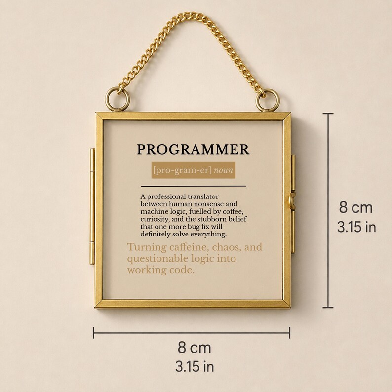 May include: A square gold-toned metal frame with a hanging chain, displaying a definition of the word PROGRAMMER. The text reads: A professional translator between human nonsense and machine logic, fuelled by coffee, curiosity, and the stubborn belief that one more bug fix will definitely solve everything. Turning caffeine, chaos, and questionable logic into working code. The frame measures 8 cm by 8 cm.