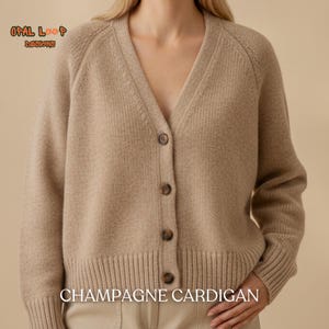 May include: A beige V-neck cardigan featuring a button-down front with four dark brown buttons, long sleeves with ribbed cuffs, and a ribbed hem. The text "OPAL LOOP DESIGNS" and "CHAMPAGNE CARDIGAN" is visible on the image in a beige tone.