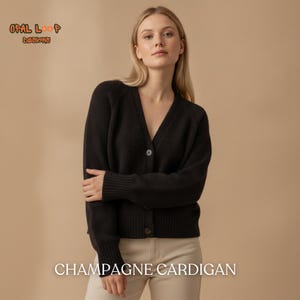 May include: A black long-sleeve cardigan with a V-neckline, ribbed cuffs, and a button-down front. The text "OPAL LOOP DESIGNS" appears in the upper left corner, and the text "CHAMPAGNE CARDIGAN" is centered at the bottom of the image.