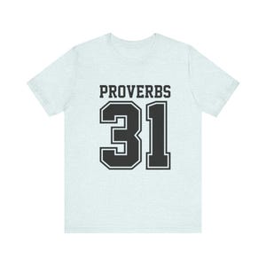 Puede incluir: Camiseta azul claro con el texto "PROVERBIOS 31" en letras negras. El número 31 está en negrita, con contorno. La camiseta es de estilo casual.