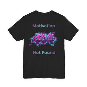 Può includere: T-shirt nera con le parole "Motivation" e "Not Found" in viola e verde acqua. Il numero "404" è al centro, con un effetto glitch. Una t-shirt grafica casual.