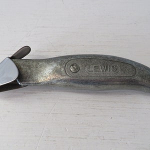 May include: A silver utility knife with a retractable blade and a black handle. The handle has the word "LEWIS" embossed on it.