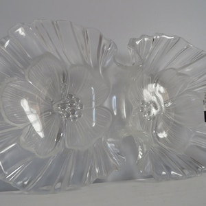 May include: A clear glass serving dish shaped like two flowers with ruffled edges. The dish is made by the brand "Mikasa".