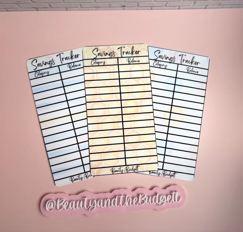 May include: Three rectangular savings tracker cards with black grid lines, headers for Category and Balance, and the text Savings Tracker. The center card features a yellow honeycomb pattern, while the outer cards have blue and white gradients. The text Beauty and the Budgett appears at the bottom of each card and on a separate pink sign.
