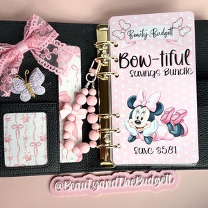 Könnte beinhalten: Ein schwarzer, strukturierter Ordner mit einer rosa Spitzenschleife, einem Schmetterlingsanhänger und einem rosa Perlenarmband. Die Einlage zeigt den Text Beauty and the Budgett, Bow-tiful Savings Bundle und Save $581 sowie eine Mausfigur.