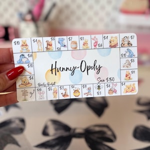 Pode incluir: Um cartão de poupança retangular intitulado Hunny-Opoly com um layout de jogo de tabuleiro apresentando personagens do Ursinho Pooh, potes de mel e valores em dólares. O centro exibe o texto Hunny-Opoly e Save $150, com Beauty Budget abaixo.