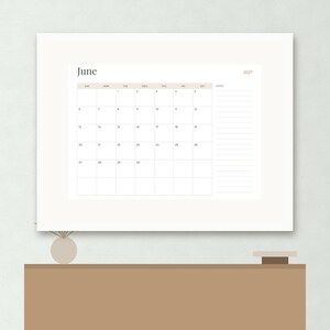 May include: A wall calendar for the month of June 2027 featuring a grid layout with days of the week, numbered dates, and a dedicated notes section on the right side. The design uses a clean white background with soft beige accents and black text.
