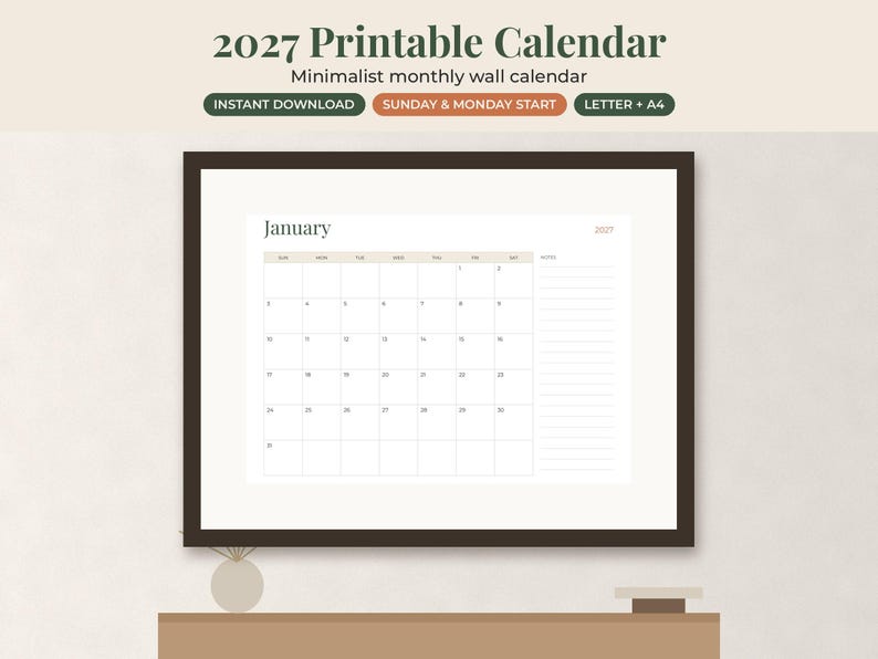 May include: A 2027 printable monthly wall calendar displayed in a dark brown frame. The calendar page shows the month of January with a grid layout, a notes section on the right, and the text 2027. The design features a neutral color palette.
