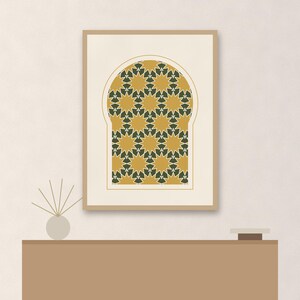 May include: A rectangular framed wall art print featuring an arched window shape filled with a repeating geometric pattern of mustard yellow and dark green stars on a cream background, displayed in a light wood frame with a thin white mat border.