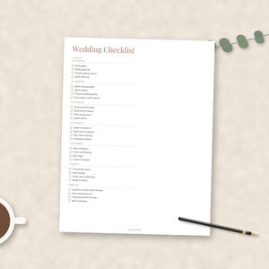 May include: A white paper sheet featuring a printed Wedding Checklist with various tasks organized by timeline, from 12+ months to the wedding day. The document includes checkboxes for each item, a cup of black coffee, and a thin black pen.