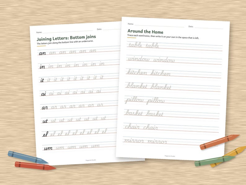 May include: Two white educational worksheets with black text for cursive handwriting practice. The left sheet is titled Joining Letters: Bottom joins, and the right sheet is titled Around the Home. Several colored crayons are placed around the papers.