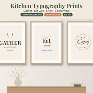 May include: Three framed wall art prints featuring kitchen typography. The first reads GATHER around the table, the second Eat well SHARE OFTEN, and the third Enjoy EVERY BITE. The designs use black and terracotta text on a light beige background.