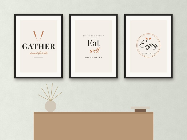 May include: Three framed wall art prints with black frames and cream backgrounds. The first print says GATHER around the table with wheat stalks. The second says Eat well SHARE OFTEN. The third says Enjoy EVERY BITE inside a circular border.