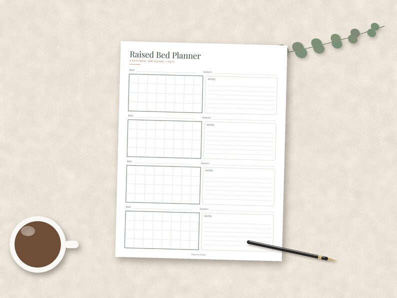 May include: A white paper sheet titled Raised Bed Planner with four sections, each containing a grid for garden layout and lined space for notes. The text reads 1 FOOT = 1 SQUARE / 1 GRID. A black pen and a small green leaf sprig are nearby.