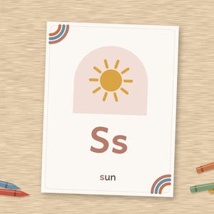 May include: A rectangular educational flashcard featuring the letter S in both uppercase and lowercase, a yellow sun icon inside a pale pink arch, and the word sun printed below. The card has small rainbow corner accents in blue and orange.