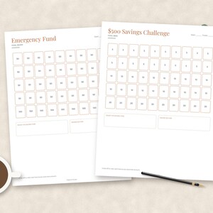 May include: Two white paper savings tracker sheets with rust-colored text and borders. One sheet is titled Emergency Fund, the other $500 Savings Challenge. Both feature grids of numbered boxes for tracking progress, with blank fields for goal dates and amounts.