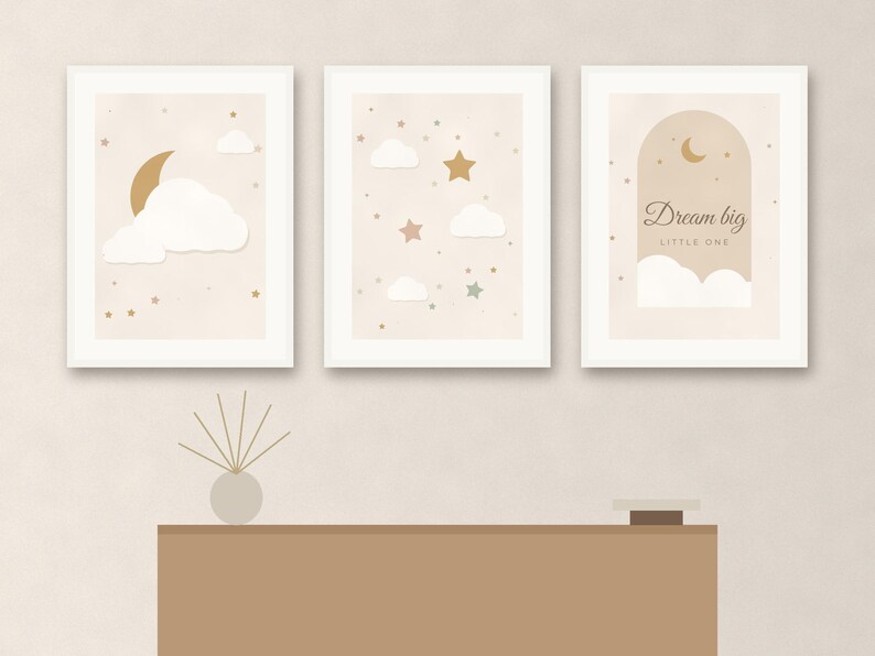 May include: Three framed wall art prints featuring a celestial theme with white clouds, gold crescent moons, and stars on a beige background. The third print includes the text Dream big LITTLE ONE inside an archway graphic design.