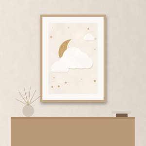 May include: A framed wall art print featuring a gold crescent moon, white clouds, and small gold stars against a light beige background. The artwork is enclosed in a simple light wood frame, displaying a celestial theme with soft colors.