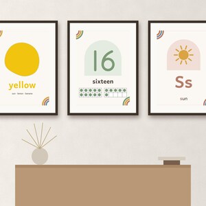 May include: Three framed educational wall art prints featuring a yellow circle with the word yellow, the number 16 with a ten-frame, and the letter Ss with a sun icon. Each print includes small rainbow accents in the corners on white backgrounds.