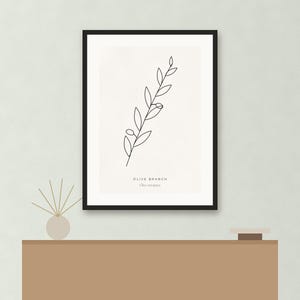 May include: A framed wall art print featuring a black line drawing of an olive branch on a white background. The text OLIVE BRANCH and Olea europaea is printed in black at the bottom center of the print. The frame is thin and black.