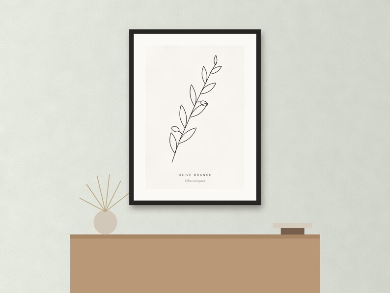 May include: A framed wall art print featuring a black line drawing of an olive branch on a white background. The text OLIVE BRANCH and Olea europaea is printed in black at the bottom center of the print. The frame is thin and black.