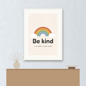 May include: A framed wall art print featuring a colorful rainbow graphic with white clouds. The text "Be kind" is printed in large black letters, followed by the smaller text "IT'S COOL TO BE KIND" centered on a light beige background.