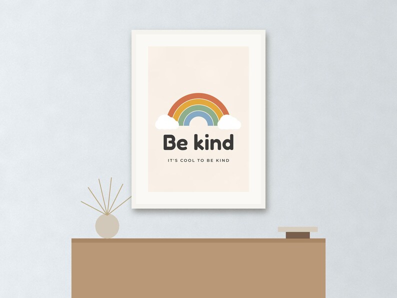 May include: A framed wall art print featuring a colorful rainbow graphic with white clouds. The text "Be kind" is printed in large black letters, followed by the smaller text "IT'S COOL TO BE KIND" centered on a light beige background.