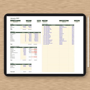 May include: A digital tablet displaying a January 2027 monthly budget spreadsheet with columns for income, bills, spending, and savings. The screen shows detailed financial data, transaction logs, and category breakdowns. A white stylus rests beside the tablet.