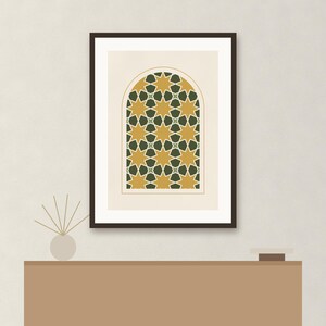 May include: A framed wall art print featuring an arched window design with a repeating geometric pattern of eight-pointed stars in mustard yellow and dark forest green, set against a light cream background within a dark brown frame.