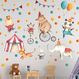 Op de afbeelding: Waterverfillustratie van een circus-thema muursticker set. Voorzien van een rood-wit gestreepte tent, een beer op een fiets en diverse dierenfiguren in feestelijke kleding, samen met sterren, ballonnen en slingers.
