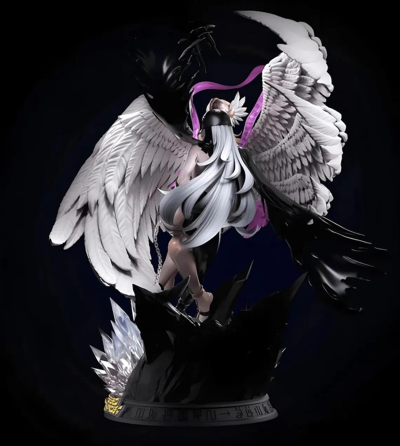 May include: A detailed figurine of a figure with long white hair, black and white wings, and a black outfit. The figure is posed on a dark, rocky base with crystal accents. The wings are spread wide, creating a dramatic contrast.