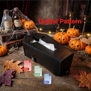 May include: A black coffin-shaped tissue box cover with a cross-shaped opening, featuring visible stitching along the edges. The image includes the red text Digital Pattern and icons for PDF, SVG, and DXF file formats on a wooden surface.
