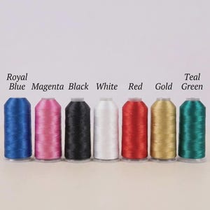 May include: Seven spools of embroidery thread in a row, with colours including royal blue, magenta, black, white, red, gold, and teal green. Each spool is labelled with its colour name. The background is white.
