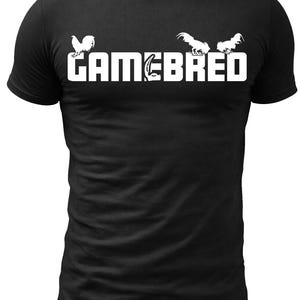 Puede incluir: Camiseta negra con el texto blanco "GAMEBRED" y tres ilustraciones de gallos blancos. La camiseta es de cuello redondo.