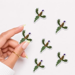 May include: Five small embroidered pheasant patches featuring brown, green, and white thread details. Each patch depicts a bird in flight with wings spread, showcasing a long tail and a purple head accent, arranged in a scattered pattern.